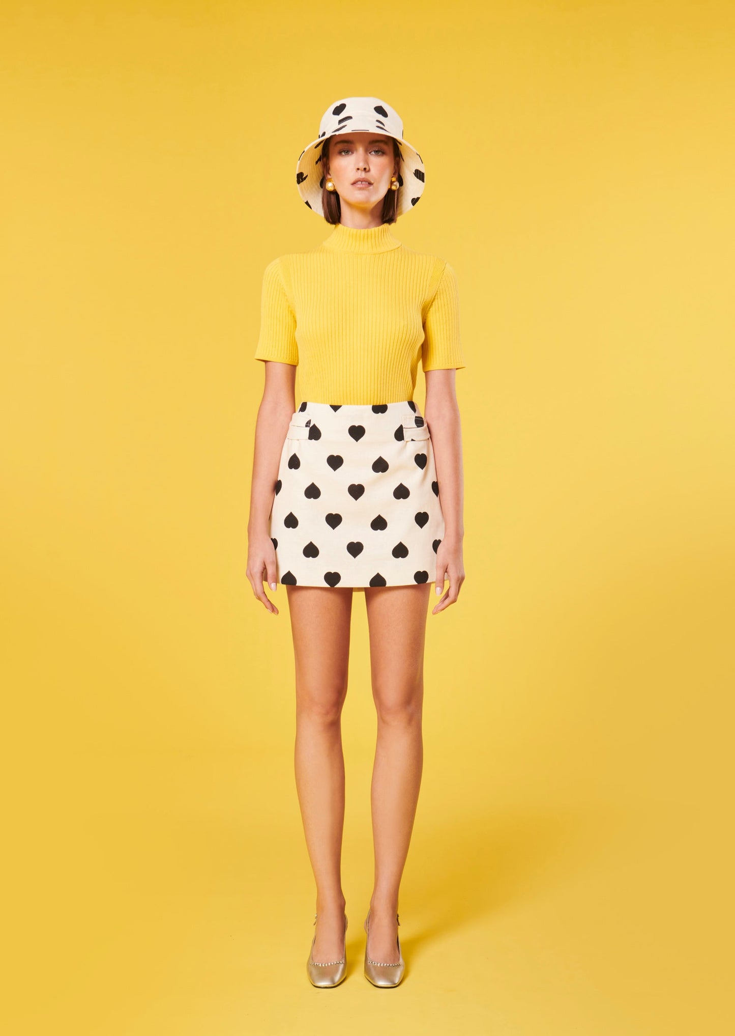 Model wearing Tara Jarmon short ecru skirt with heart print.