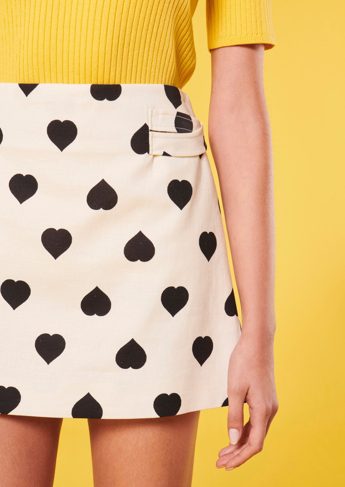 Short ecru skirt with black heart print and criss-cross straps.