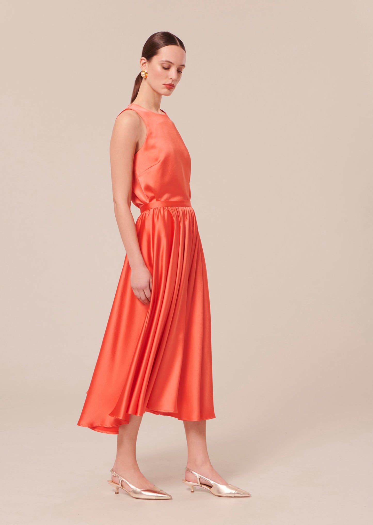 Model wearing Tara Jarmon long satin coral skirt with matching satin coral top.