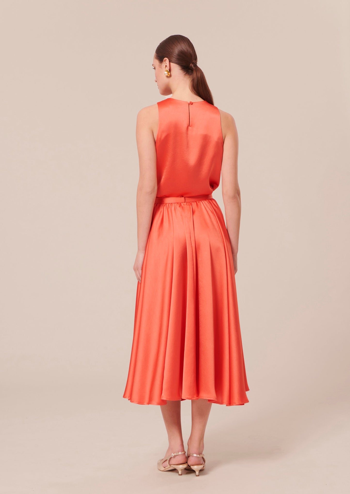 Flowing coral satin skirt with fitted waist.