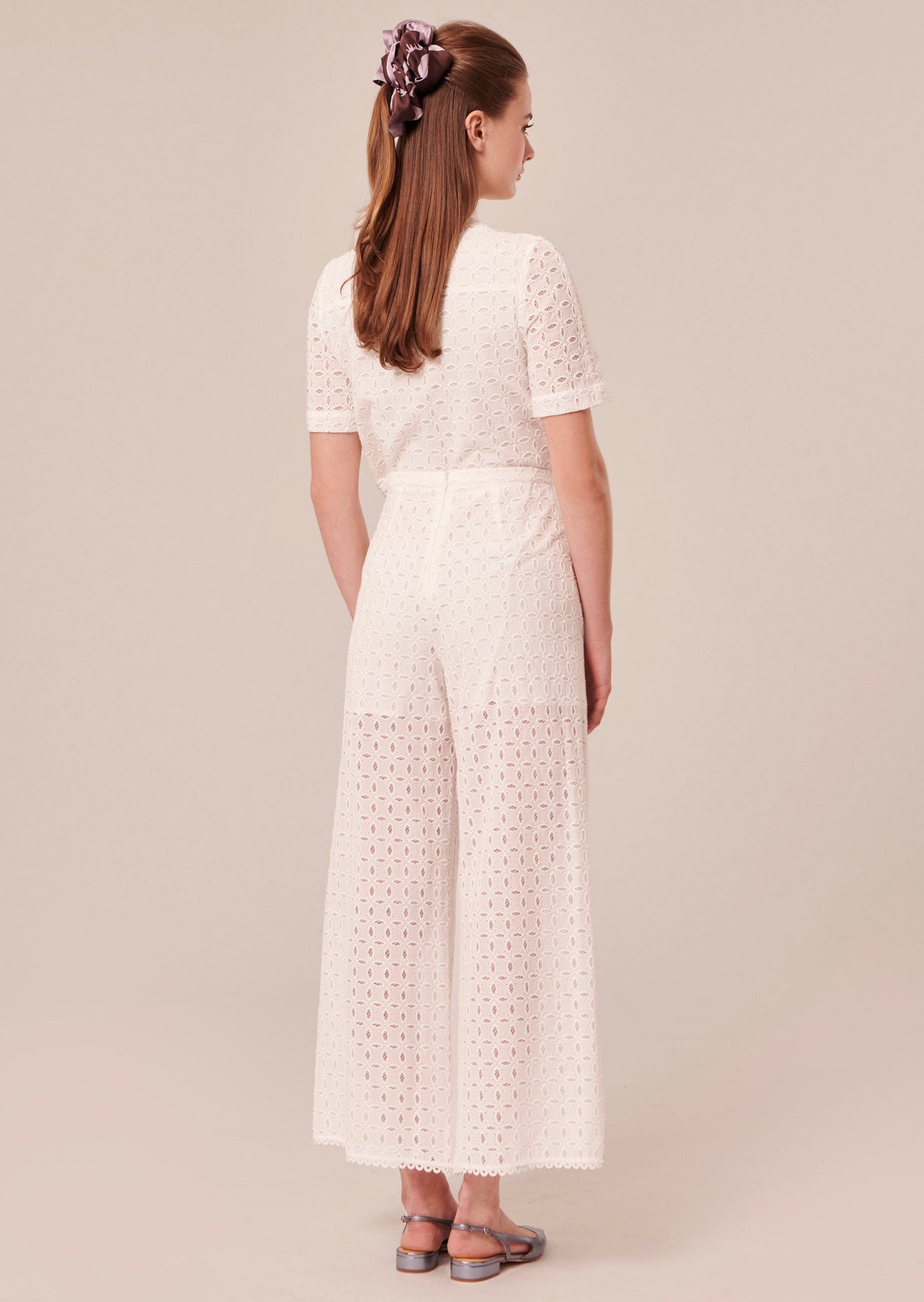 Model wearing Tara Jarmon white high-waisted pants with a wide leg.