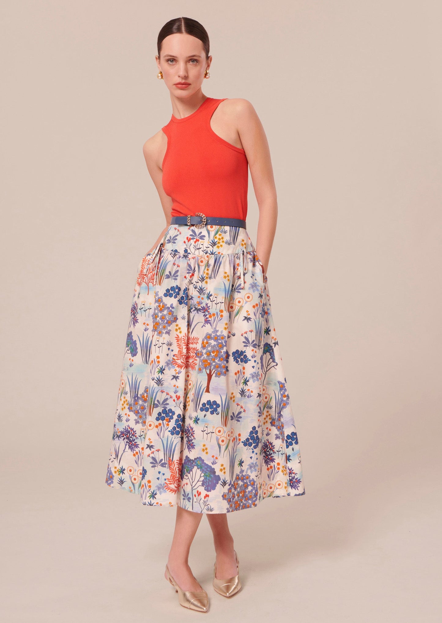 Model wearing Tara Jarmon coral sleeveless pull with colorful long skirt.