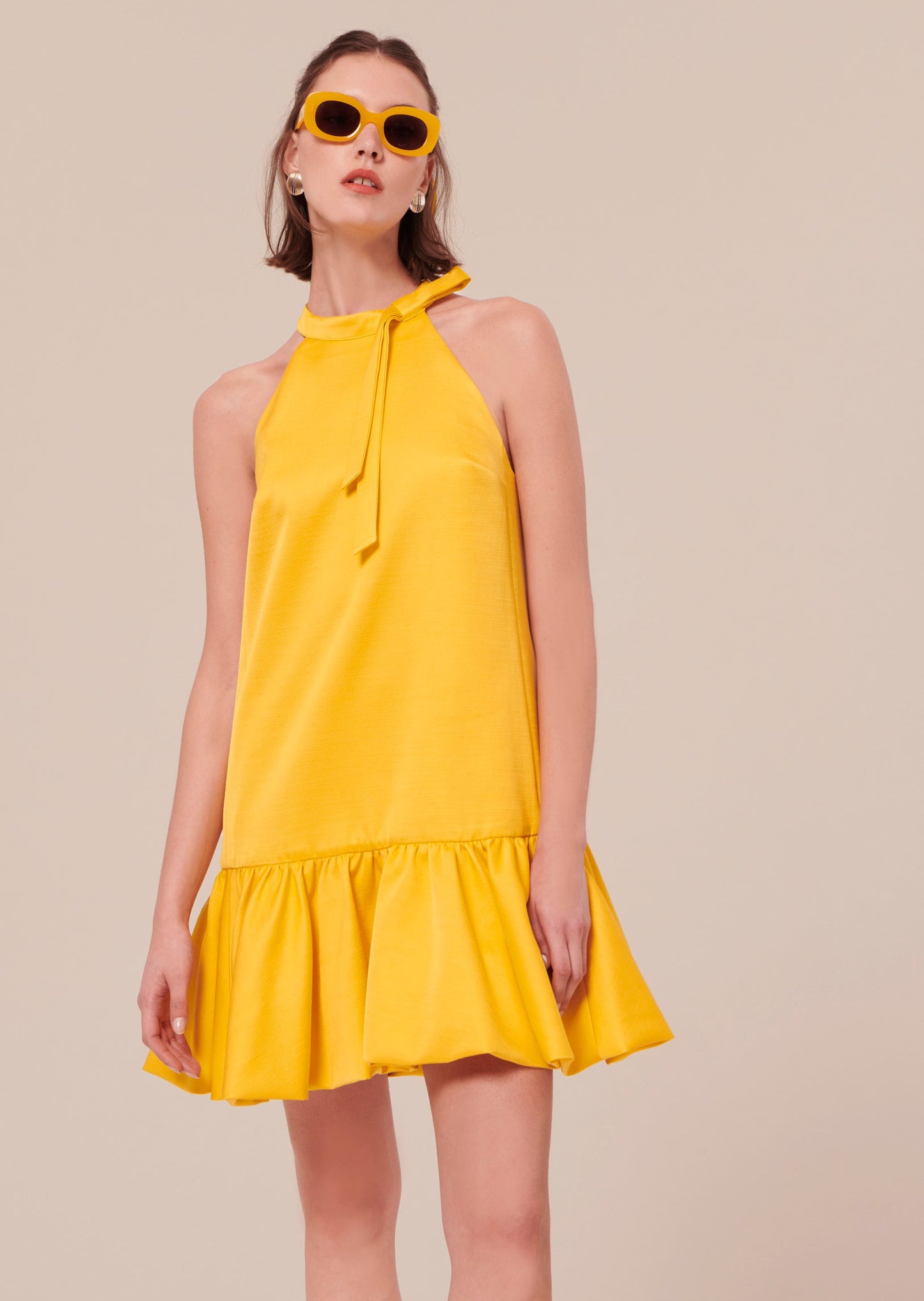 Model wearing Tara Jarmon Yellow Satin Short Dress, with yellow sunglasses.