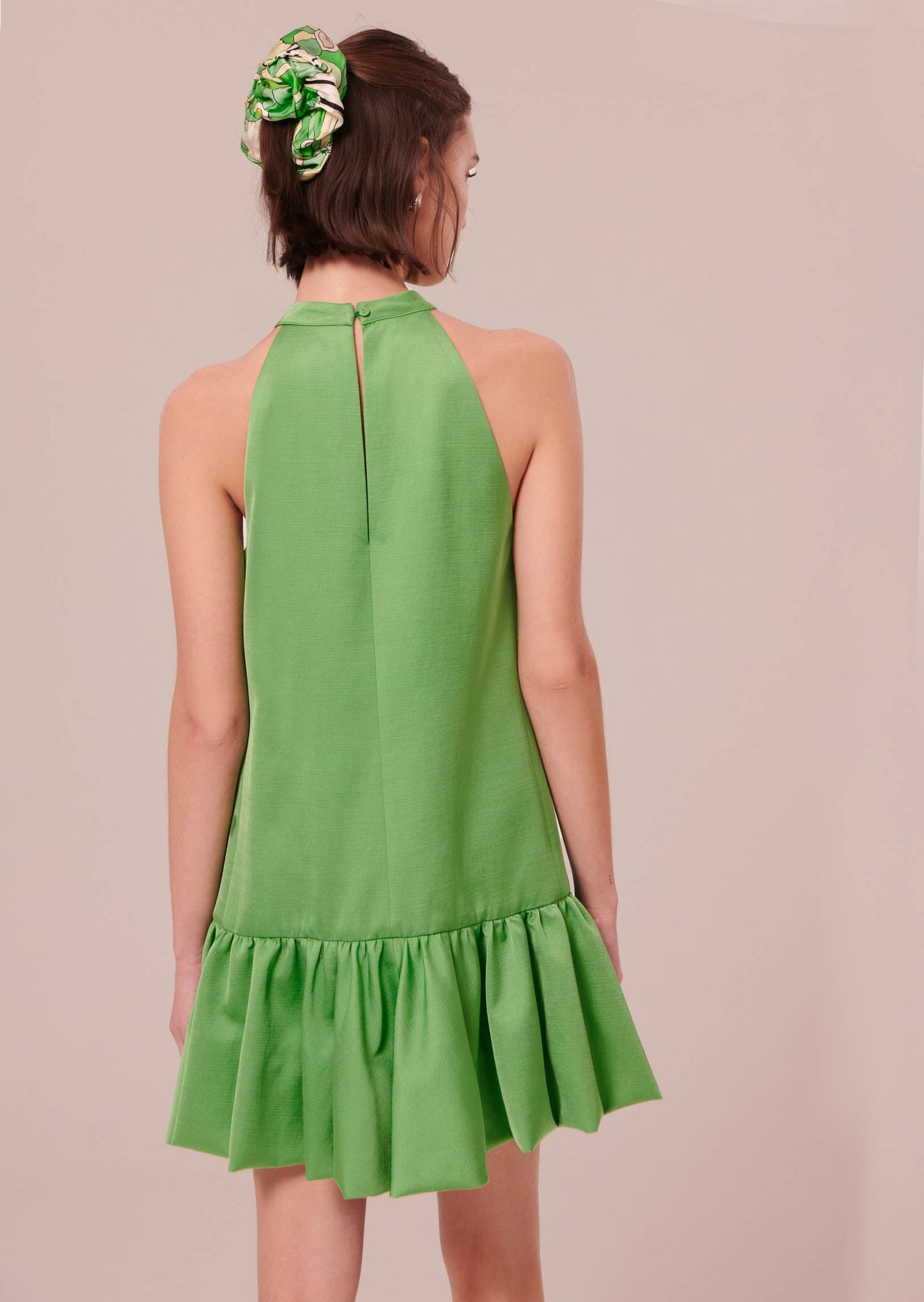 Sleeveless green satin dress that closes with a button on the back.