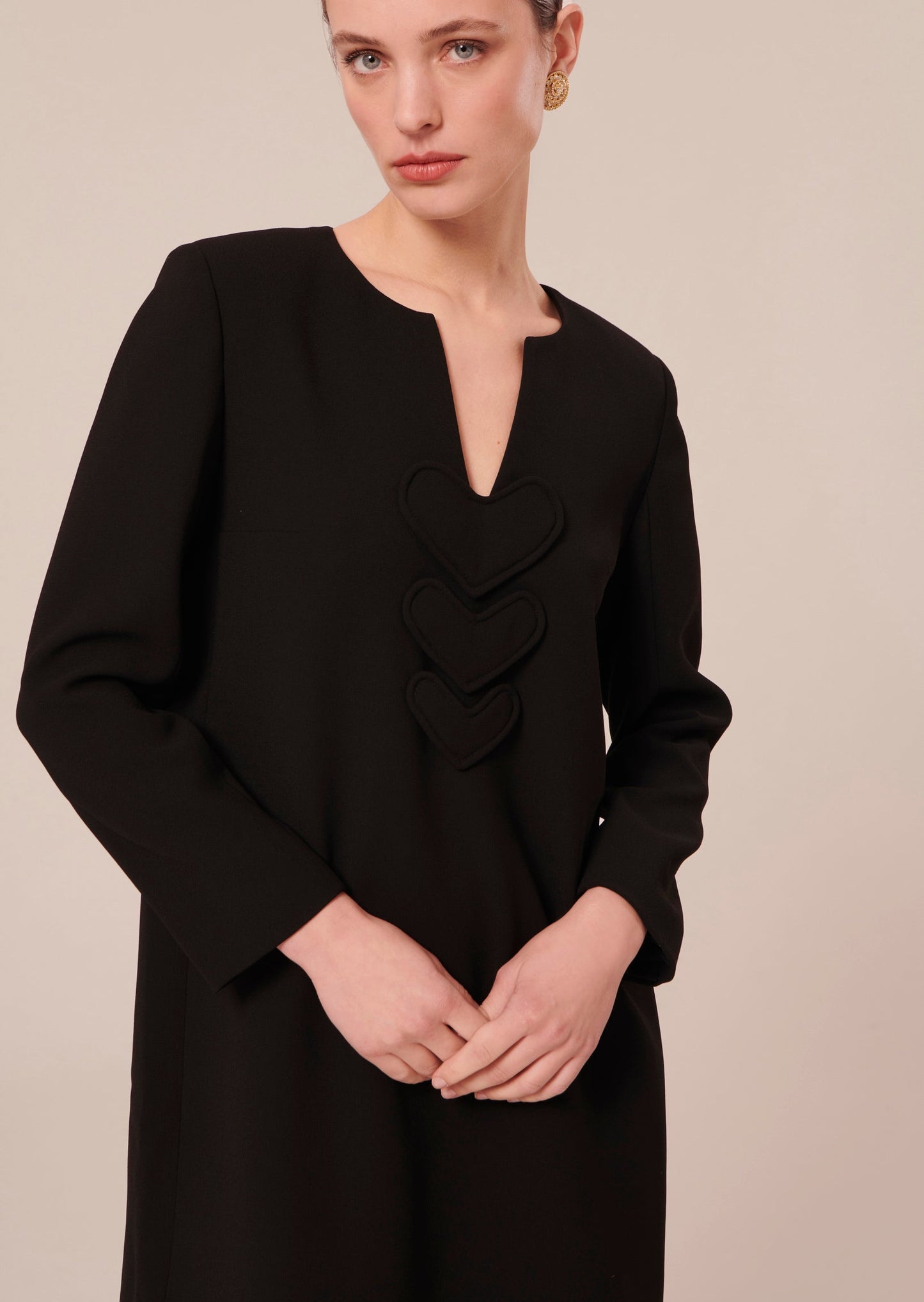Long sleeves, short black dress with V-neckline.