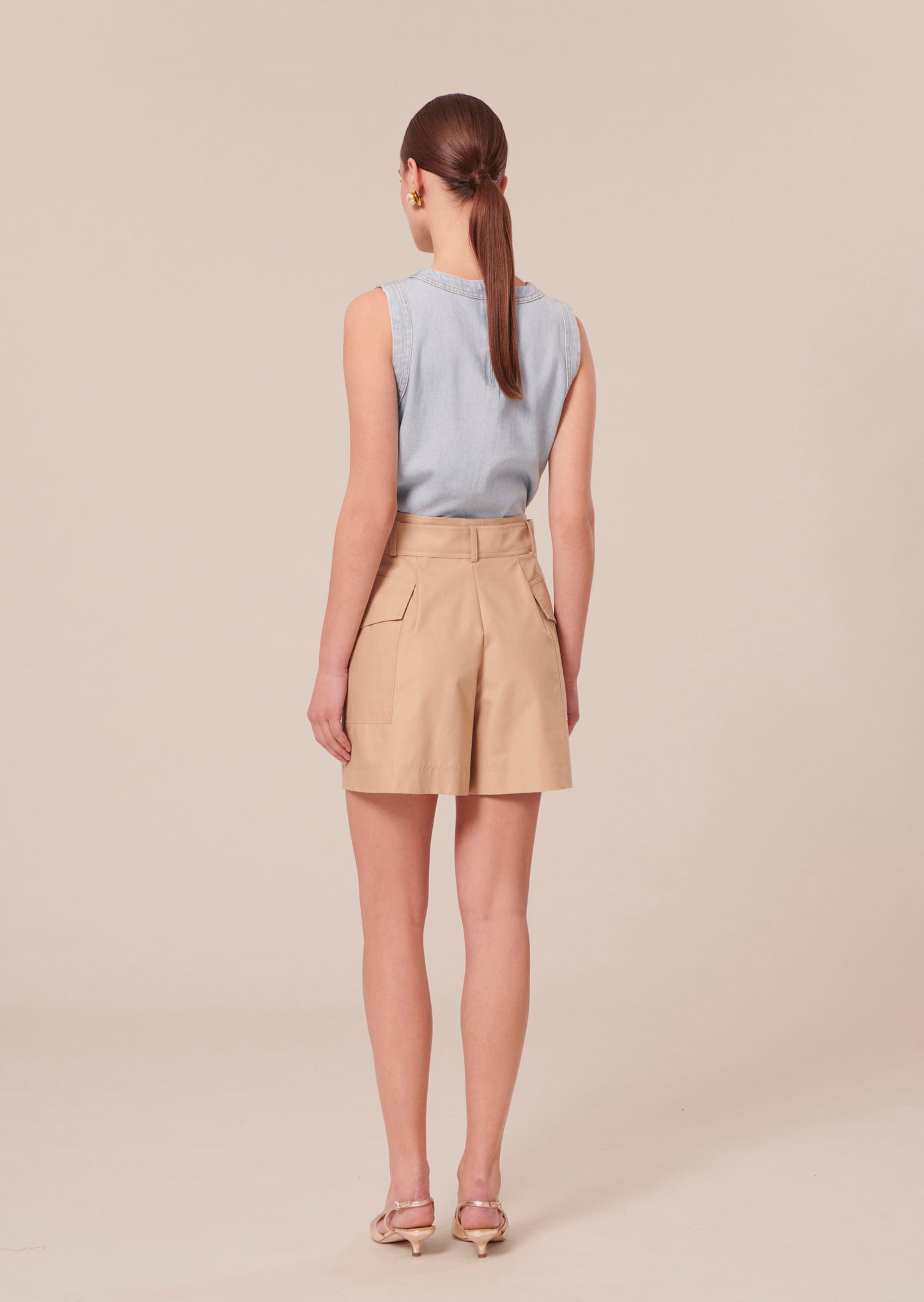 Slightly oversized, high-waisted beige shorts.