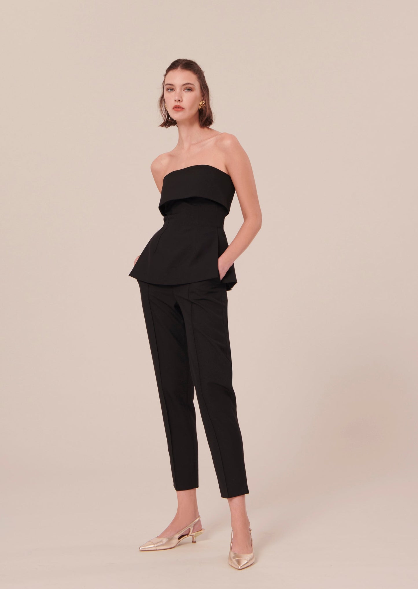 Strapless black top with small side slit matching with a black pants and gold leather pumps.