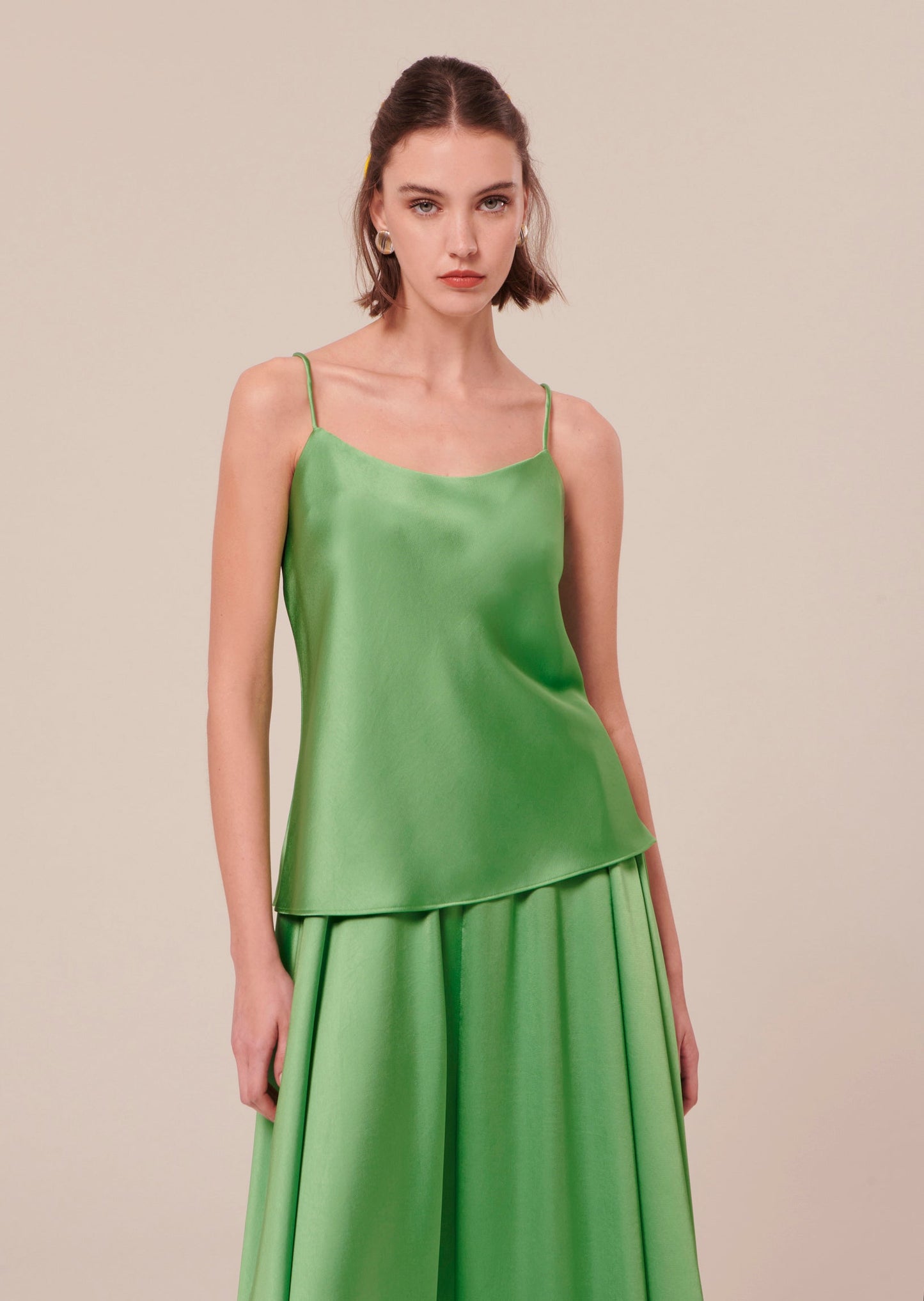 Green satin tank top with thin straps, matching with a flowing long green satin skirt.