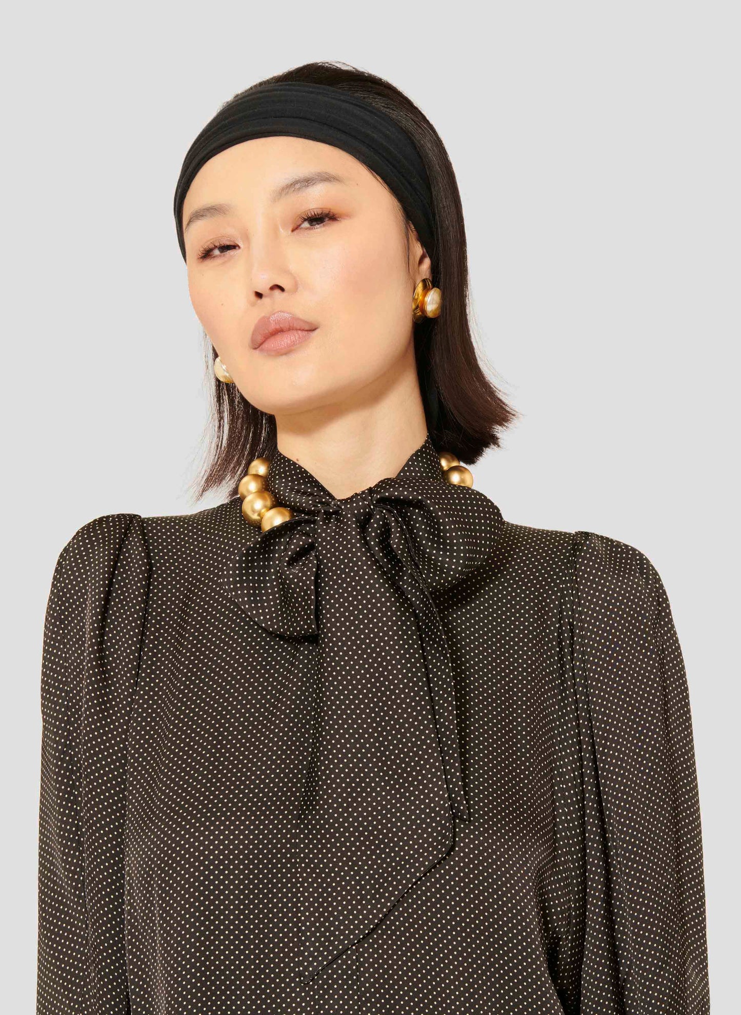 Model wearing Tara Jarmon black polka dot shirt with long puffed sleeves.