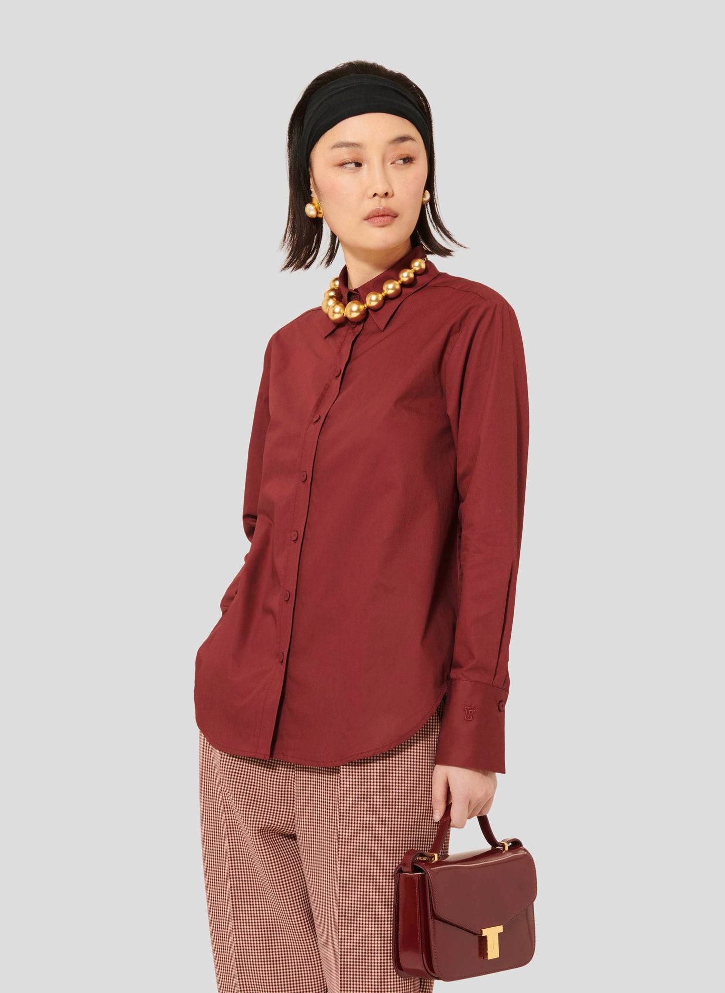 Tara Jarmon women burgundy cotton poplin long sleeves shirt with gold pearl necklace.