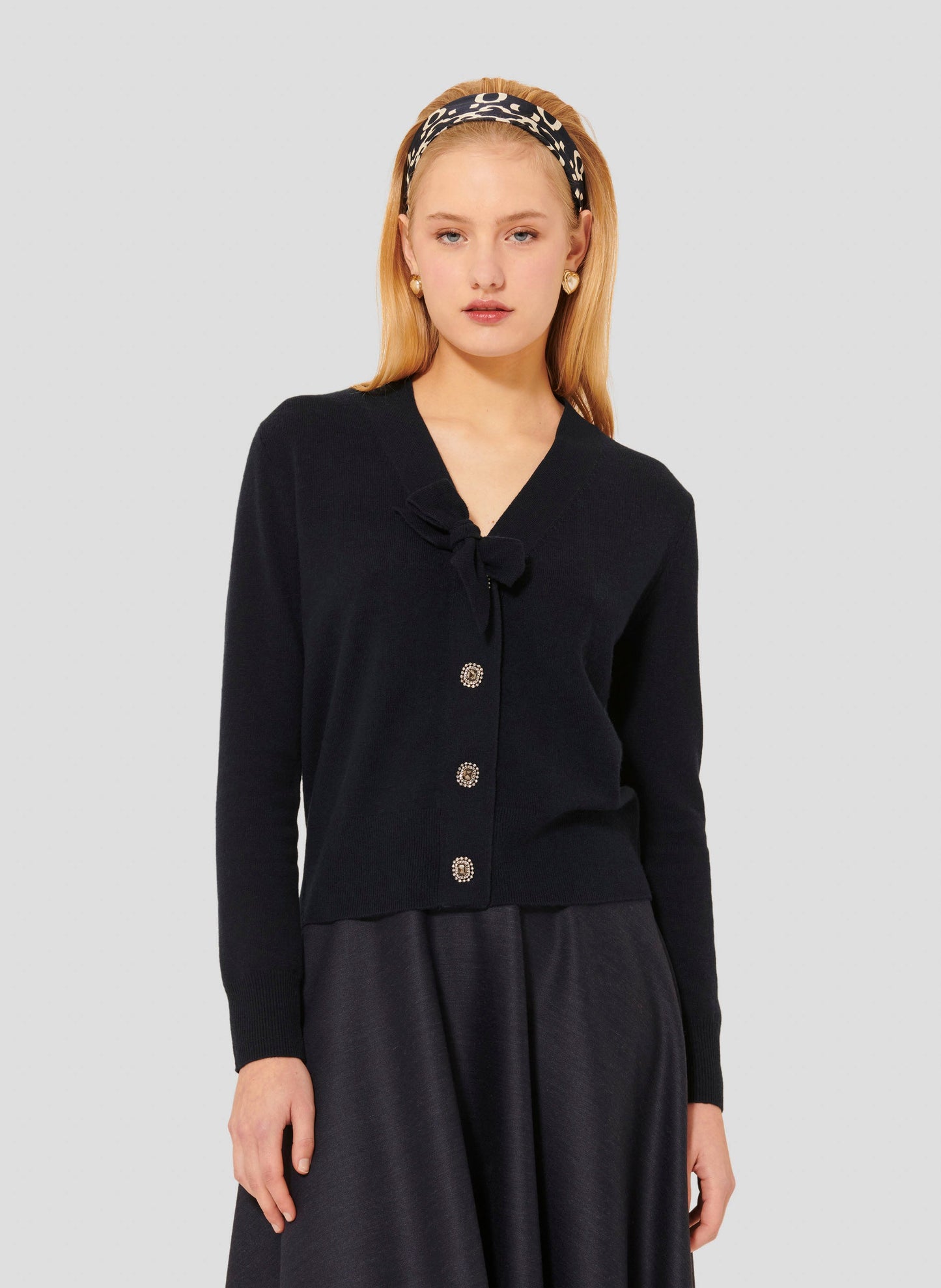 Model wearing Tara Jarmon midnight blue colored wool sweater with V-neck and tie detail.