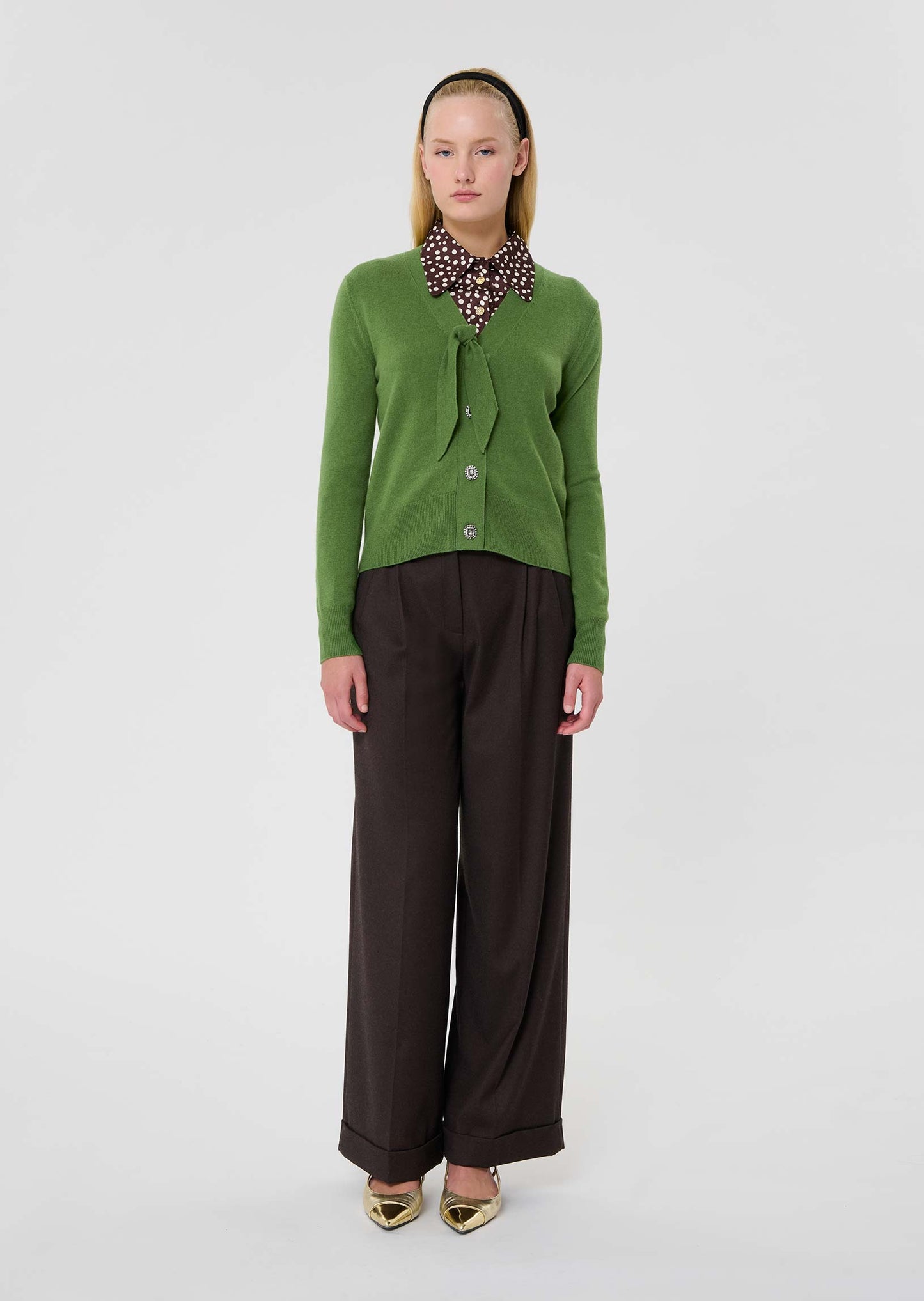 Model wearing Tara Jarmon green colored wool sweater with V-neck and tie detail.