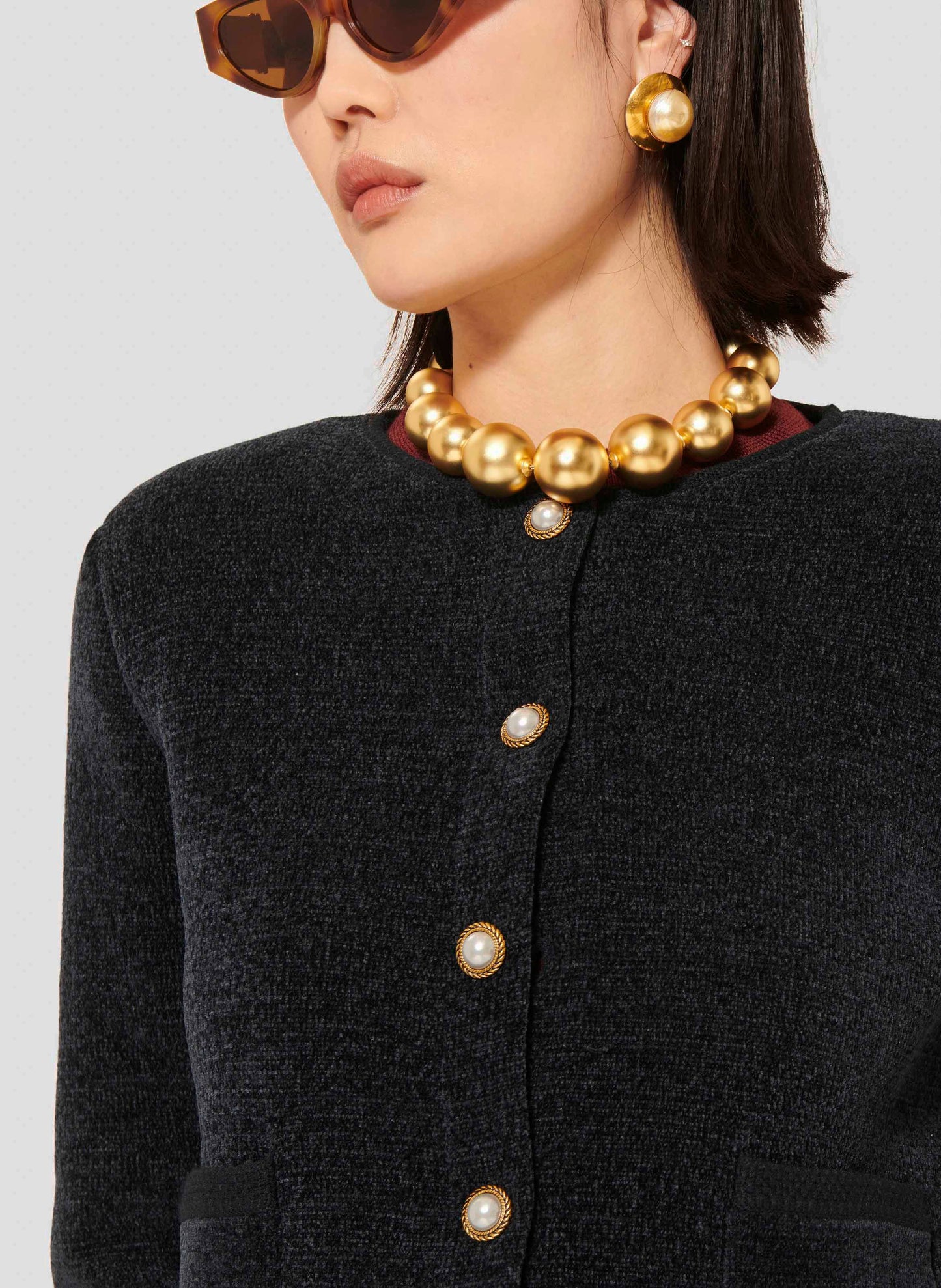 Blue cardigan with round collar, long sleeves, buttoned cuffs and a short straight cut.