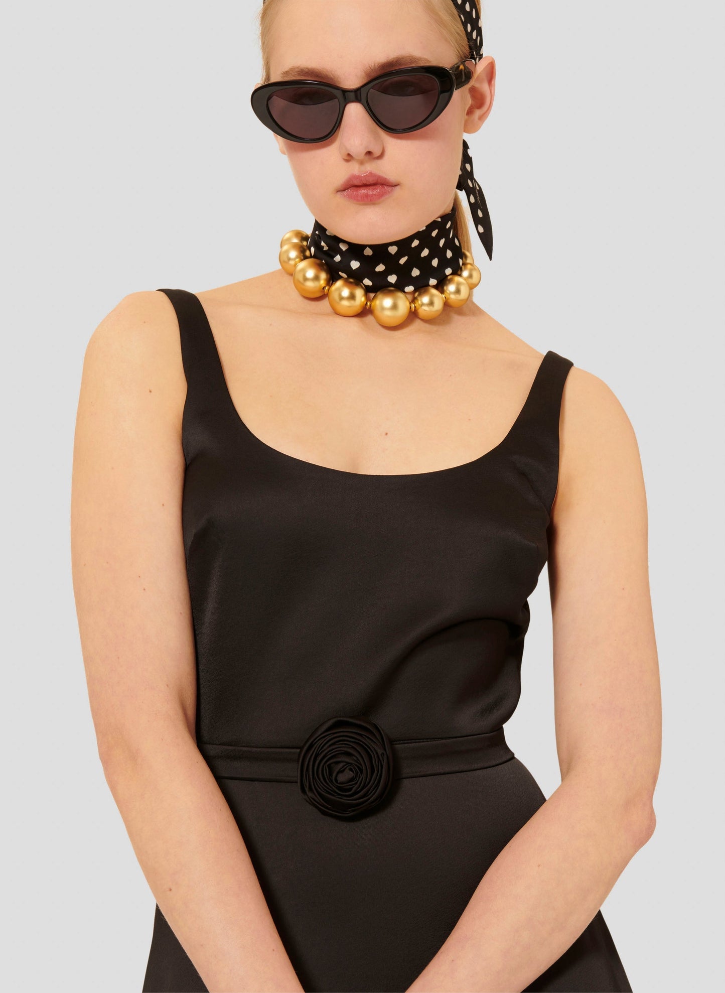 Sleeveless black satin dress with fitted waist and belt.