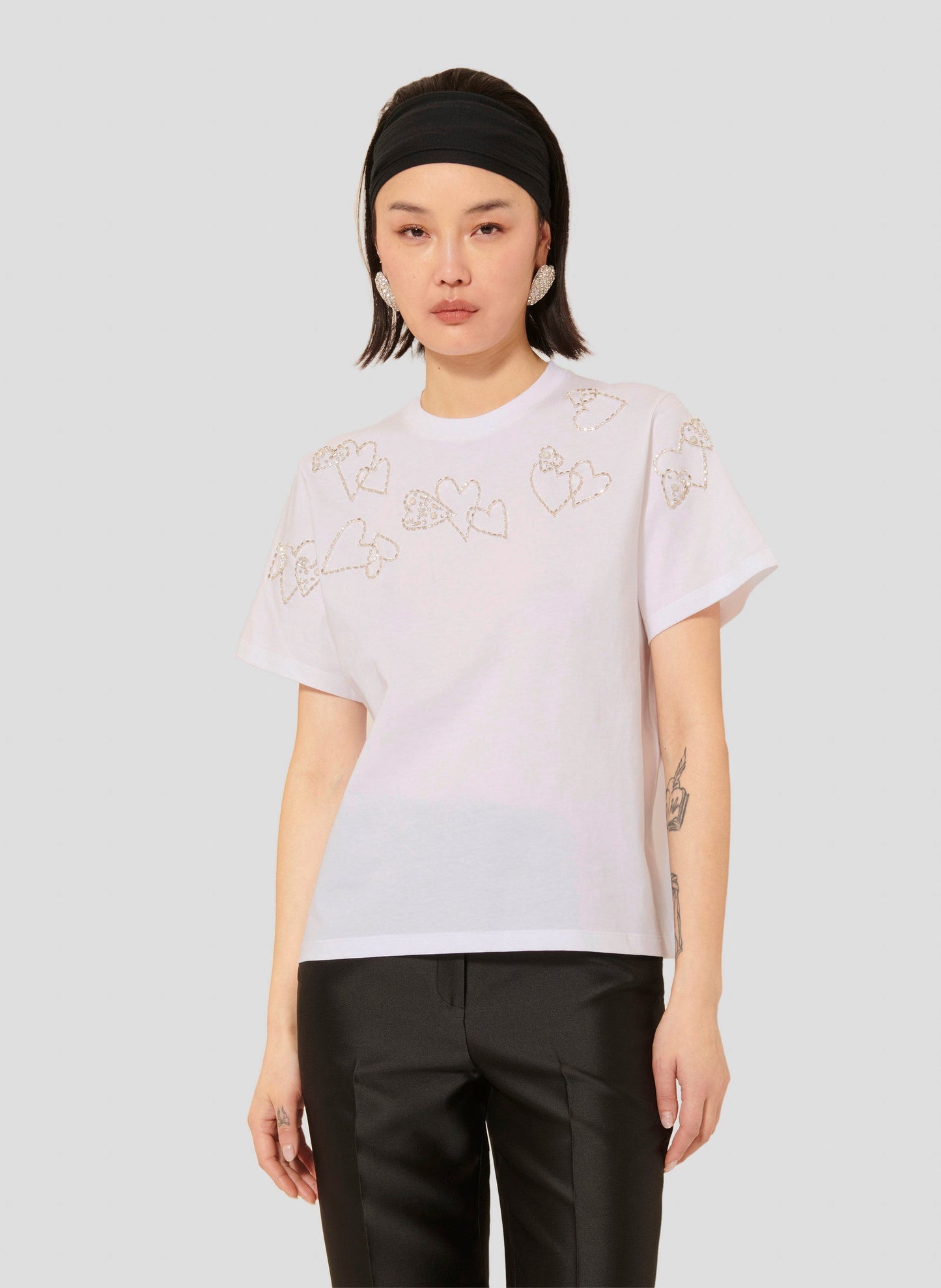 Model wearing Tara Jarmon White Cotton T-Shirt with Heart Rhinestones and Embroideries.