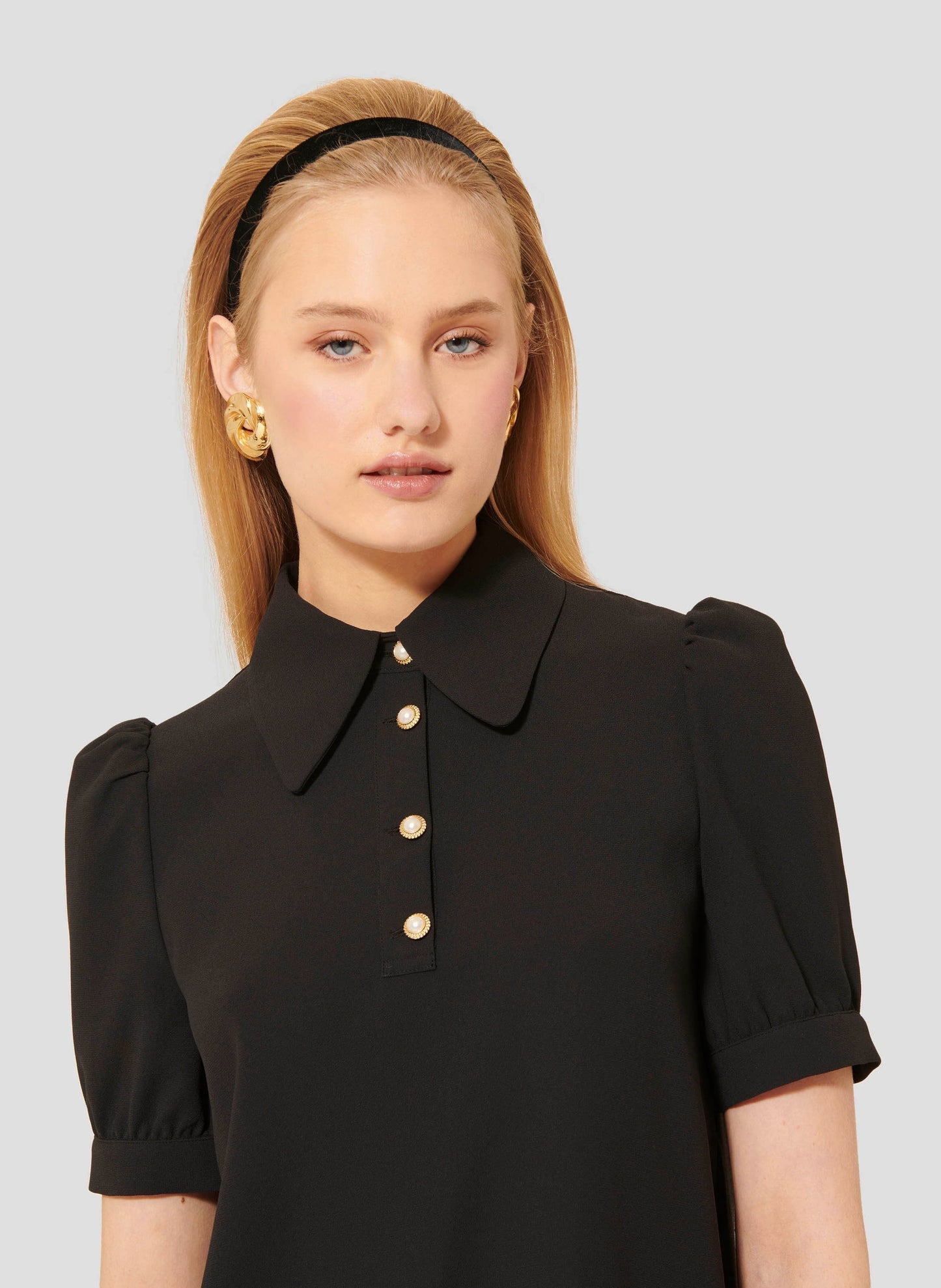 Model wearing Tara Jarmon black crepe top with short balloon sleeves.