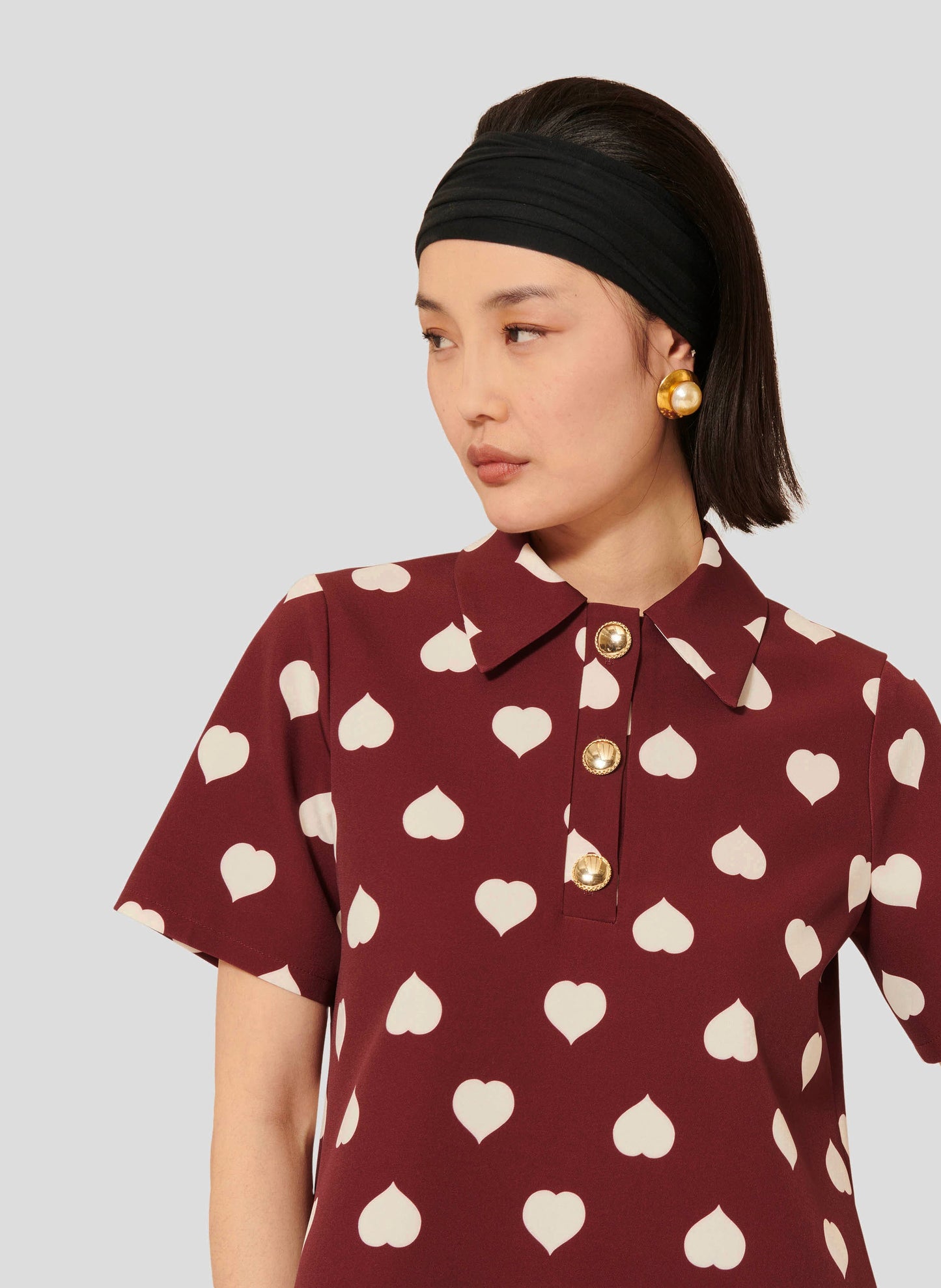 Short-Sleeve Burgundy Top with Gold Button-Front Closure and Heart Detail.