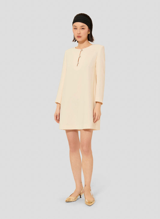 Model wearing Tara Jarmon short ecru crepe dress with long sleeves and a round neckline.