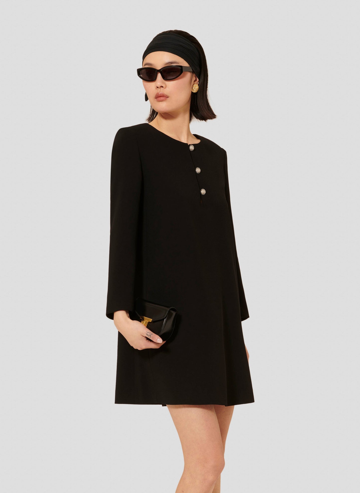 Model wearing Tara Jarmon short black crepe dress with long sleeves and a round neckline.
