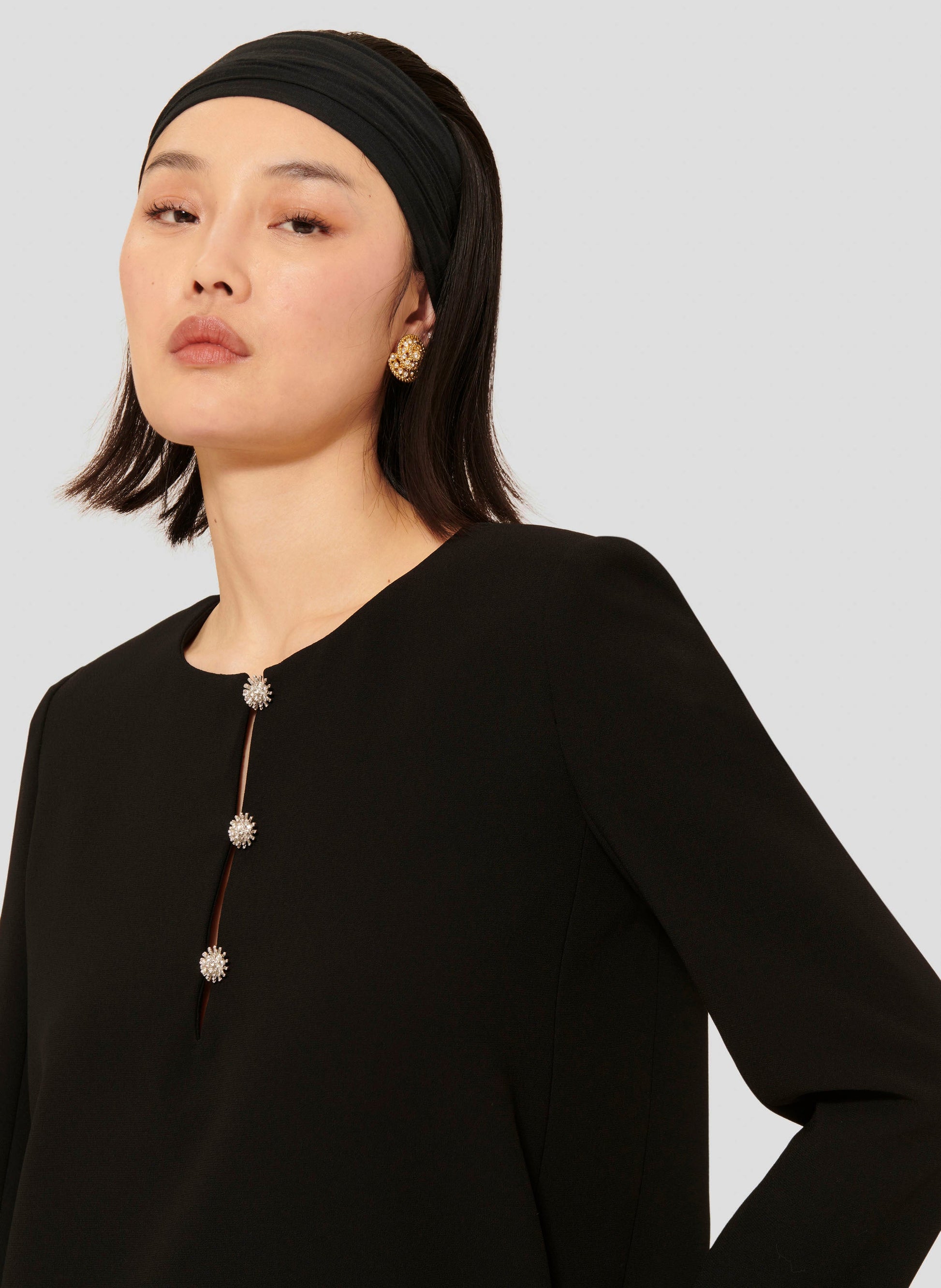 Long sleeves black dress with round neckline and gold buttons. 