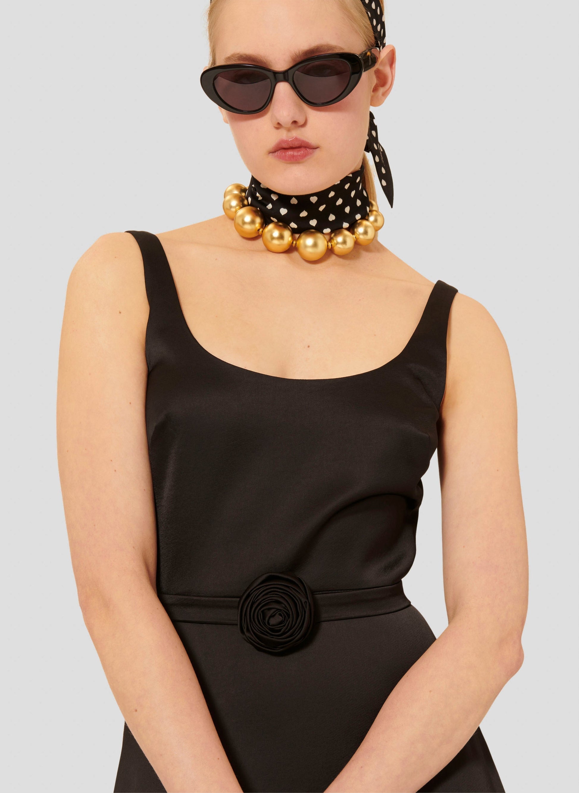 Sleeveless black satin dress with fitted waist and belt.  